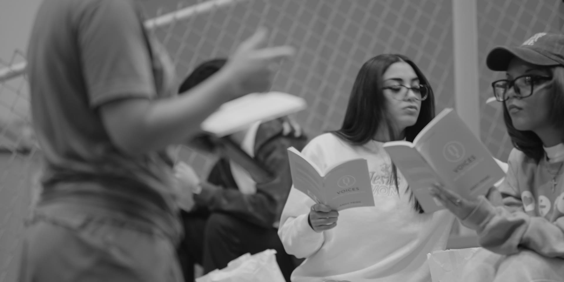Teens reading together from a devotional book, in a black and white photo from the Philly FCA year-end appeal